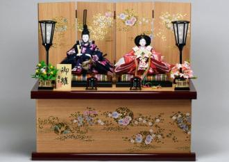 木目調の収納箱・屏風です。京都西陣金襴の桜柄のお衣裳で、飾台屏風の金彩桜柄とマッチさせてあり、明るい感じの収納飾りです。岩槻人形伝統工芸士の大豆生田博さんの工房で製作されたお顔は、伝統を踏まえながら現代風にまた上品に仕上げました。　